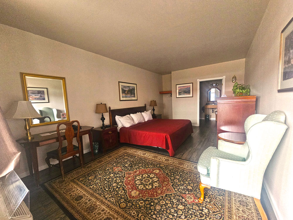 ADA room with view of bed with red bedspread, chair and desk